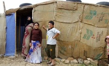Azmat and two of her four children stand outside their makeshift shelter in an informal tented settlement in Akkar district, north Lebanon.
