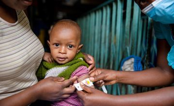 Jane holds her baby Mark (11 months) as a nurse uses a MUAC band to check his nutrition status. Photo: Ed Ram / Concern Worldwide / Kenya (2020)