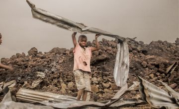 Amani (12) from the Buhene district in the north of Goma, collects the rubble after a volcanic eruption. Photo Esdras Tsongo Concern Worldwide