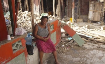 Woman sits on wall surrounded by the ruins of a building destroyed during the earthquake in Haiti