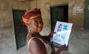 Kumba Tabe Mansaray wife of the Town Chief hanging a Concern Worldwide printed COVID-19 flyer at her residence in Bassaia Village Tonkolili District Sierra Leone Photo: Mohamed Saidu Bah / Concern Worldwide.