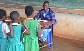 A Malawian teacher grades her students' exercises in class