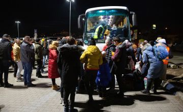 Families seeking refuge from conflict in Ukraine board buses at a reception centre in Przemyśl, Poland. Photo: Kieran McConville
