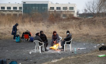 People sitting around small fire at Polish border