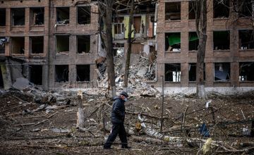 A man walks in front of a destroyed building after a missile attack in the town of Vasylkiv, near Kyiv, on February 27, 2022. Photo by DIMITAR DILKOFF/AFP via Getty Images