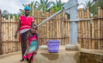 Liberian woman with her daughter by a new water pump