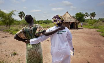 A pregnant South Sudanese woman walks with her midwife into a mobile health clinic