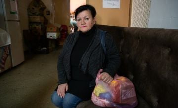 Woman sitting on couch and holding plastic bag of food