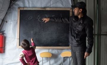 Syrian refugee boy learning from a teacher in a tented classroom in Lebanon