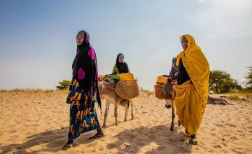 Chadian women traveling great distances to gater water in a desert.