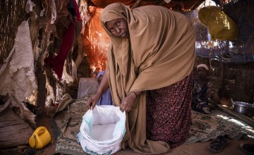 Cibaado Geedi Cali opens a bag of sugar in her home in Qaloocato, Odweine, Somaliland. Cibaado and her family used to grow corn, watermelon, tomato and grain but they haven't had a harvest in two years -there just hasn't been enough rain. The last harvest was December 2020. Photo: Ed Ram/Concern Worldwide