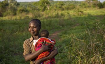 A woman from Central African Republic holding her infant son aon the small plot of land the family tends near their home