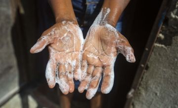 Rosette Mesalien 34, a beneficiary of Concern Worldwide, washes her hands with liquid soap in front of their home in Cite Soleil, a district of Port-au-Prince, Haiti. Photo: Dieu Nalio Chery / Concern Worldwide.