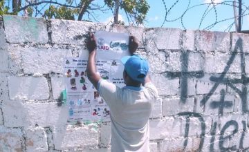Man putting up poster on wall