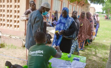 People signing for and receiving kits from the Concern team at Ramesim site, Burkina Faso. The support included unconditional multi-purpose cash transfers and hygiene promotion campaigns. Photo: Jean-Paul Ouedraogo / Concern Worldwide.