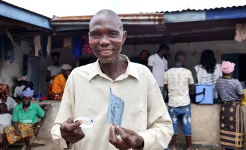 Victor S Canteh (46) holds his vaccination card after receiving his second vaccination in Madif. 'I am very glad I was able to get my second dose.’ Photo: Conor O'Donovan / Concern Worldwide.