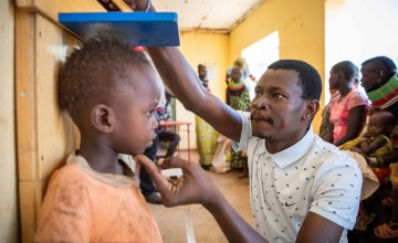 A man screening a young boy for stunting at a malnutrition clinic in northern Kenya