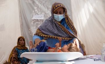 A woman weighing her child at a mobile clinic in Pakistan
