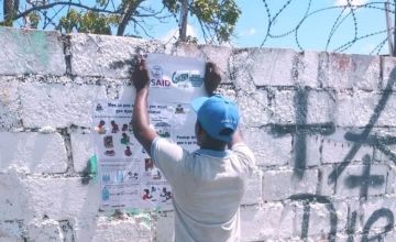 Humanitarian workers putting up posters on cholera prevention in Haiti following a 2022 outbreak