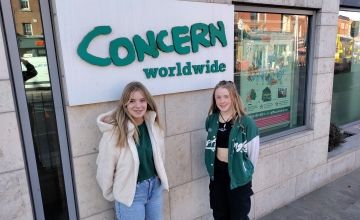 Two students at TY Academy stand in front of a Concern Worldwide sign