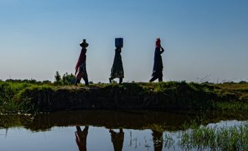 Women affected by the 2022 floods in Pakistan carrying drinking water through Jacobabad
