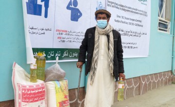 Man wearing face mask and holding cane outside health clinic