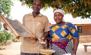 Man holding fish, next to wife holding plate of fish food