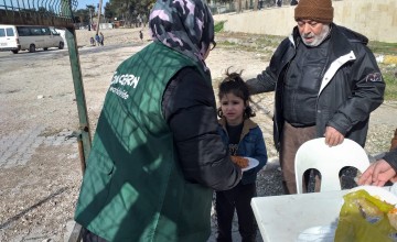 A Concern staff member hands a plate of hot food to a young girl in Turkey