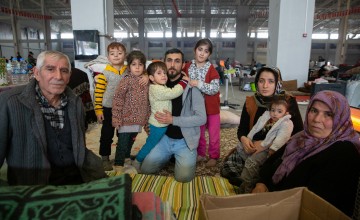 Family of elderly, middle aged and children kneeling on ground in large hall