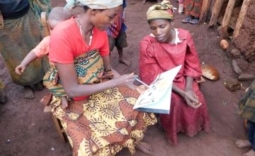 A maternal care group leader in Burundi talks with one of her group members