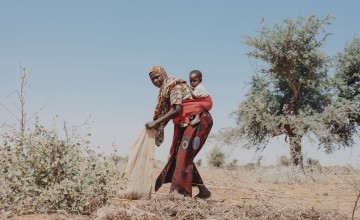 Nigerien woman prepares her land for the beginning of the rainy season with her infant daughter on her back