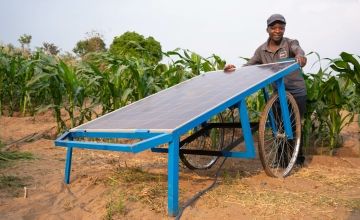 Farmer Mcfreson Aaron stands with solar water pump in crop field in Malawi