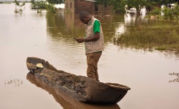 Concern staff member Tommy Chimpanzi stands in canoe in floodwater 