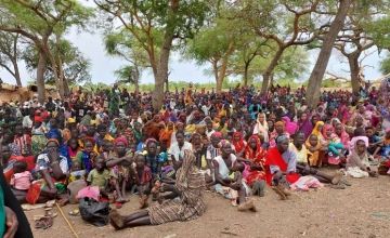 Crowd of Sudanese refugees sitting on the ground