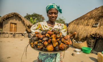 Mama Yambo Mbuyu wa Kyungu, holding platter of fruit