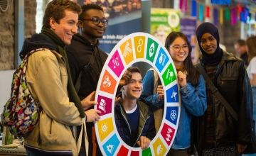 Five students smile and pose with Global Goals sign