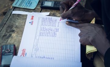 Hands writing details in a cash transfer notebook