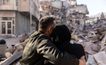 Woman and man embracing as they look at rubble caused by Turkiye earthquake