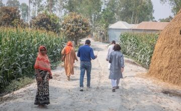 Community members walk along a road that has been raised six feet above the flood line, as part of the Zurich Flood Resilience Programme. Gavin Douglas / Concern Worldwide