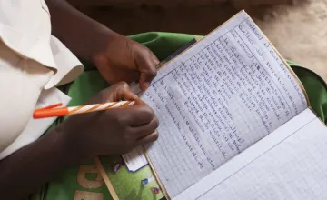 Amida Tuyishimire (14), daughter of Violette Bukeyeneza with her school books and pens for the education she is now able to receive because of the Graduation Program at her home in Bukinanyana, Cibitoke, Burundi