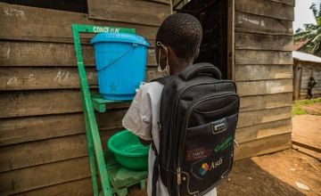 Baraka Mbayo, a primary student in Birambizo, DRC, washes his hands before entering the classroom