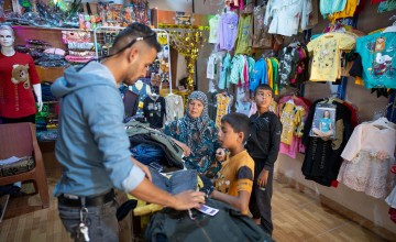 Shahinaz* buys new clothes for her grandsons after receiving cash support at a camp in north-west Syria on 22 June 2023. As part of Concern Worldwide’s response to the Syria-Turkey earthquake, cash assistance is distributed to displaced families living in camps and temporary shelters to meet their immediate basic needs. After an informational session, each household receives a cash voucher at the distribution point. Photo: Karam Al-Masri/Arete/DEC