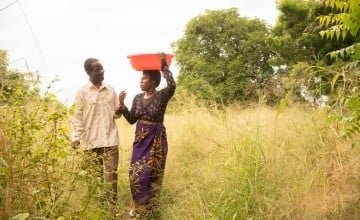 Stone and Rose walk to their garden to pick vegetables to sell at market. After finishing the Umodzi training, Stone takes an active part in Rose's farming business. (Photo: Chris Gagnon / Concern Worldwide)