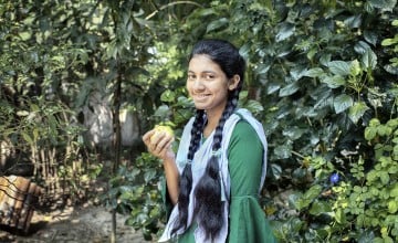 Fifteen year old Sharmin Akter is eating guava, which is a nutritious fruit. She often participates in group discussions in the yard meeting conducted by Concern Worldwide and its partner organizations to gain knowledge about healthy food, health and hygiene, gender, and social safety issues. The Collective Responsibility, Action, and Accountability for Improved Nutrition (CRAAIN) project have educated them to act right about nutrition and safeguarding health. Photo: Mohammad Rakibul Hasan/Concern Worldwide