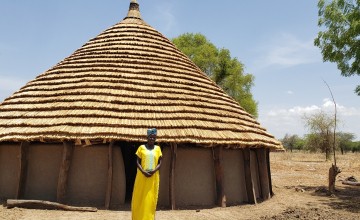 Abuk Wieu in front of her tukul house constructed using savings from the Village Savings and Loans Association.