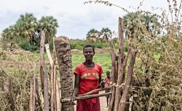 Regina Erot stands at the fence guarding her plot of land in Turkana