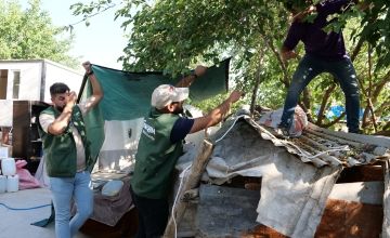 Concern staff build a sun shade for Meryem and Mehmet Kaya during a distribution at the remains of their home in Malatya