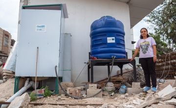 Erva* with a water tank and latrine her family received from Concern