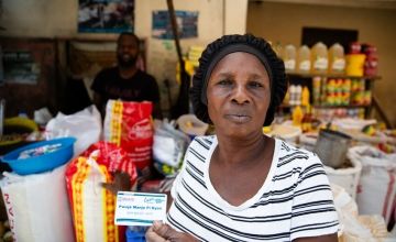 A participant in Concern's food voucher system buying provisions from a vendor in Cite Soleil, Haiti