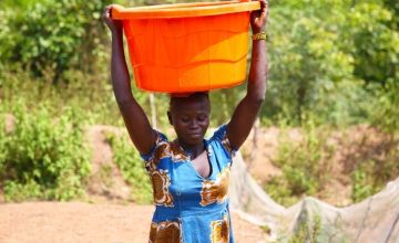 A woman carries water from a Concern-constructed water point at Boyali in Central African Republic, which is now managed by the local community. The existing water source was protected from flooding and the access point raised for better access.